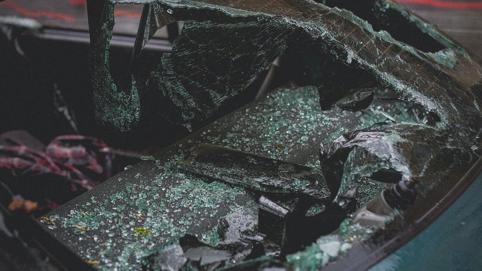 Detailed view of shattered car windshield after accident, emphasizing damage and broken glass.
