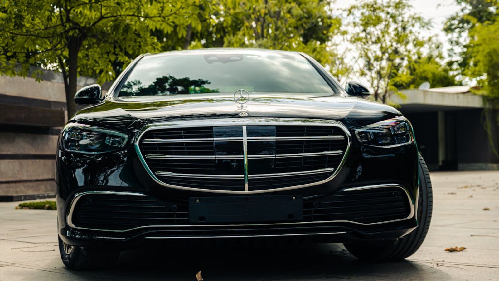 Front view of a luxurious black Mercedes Benz parked in a serene outdoor setting.