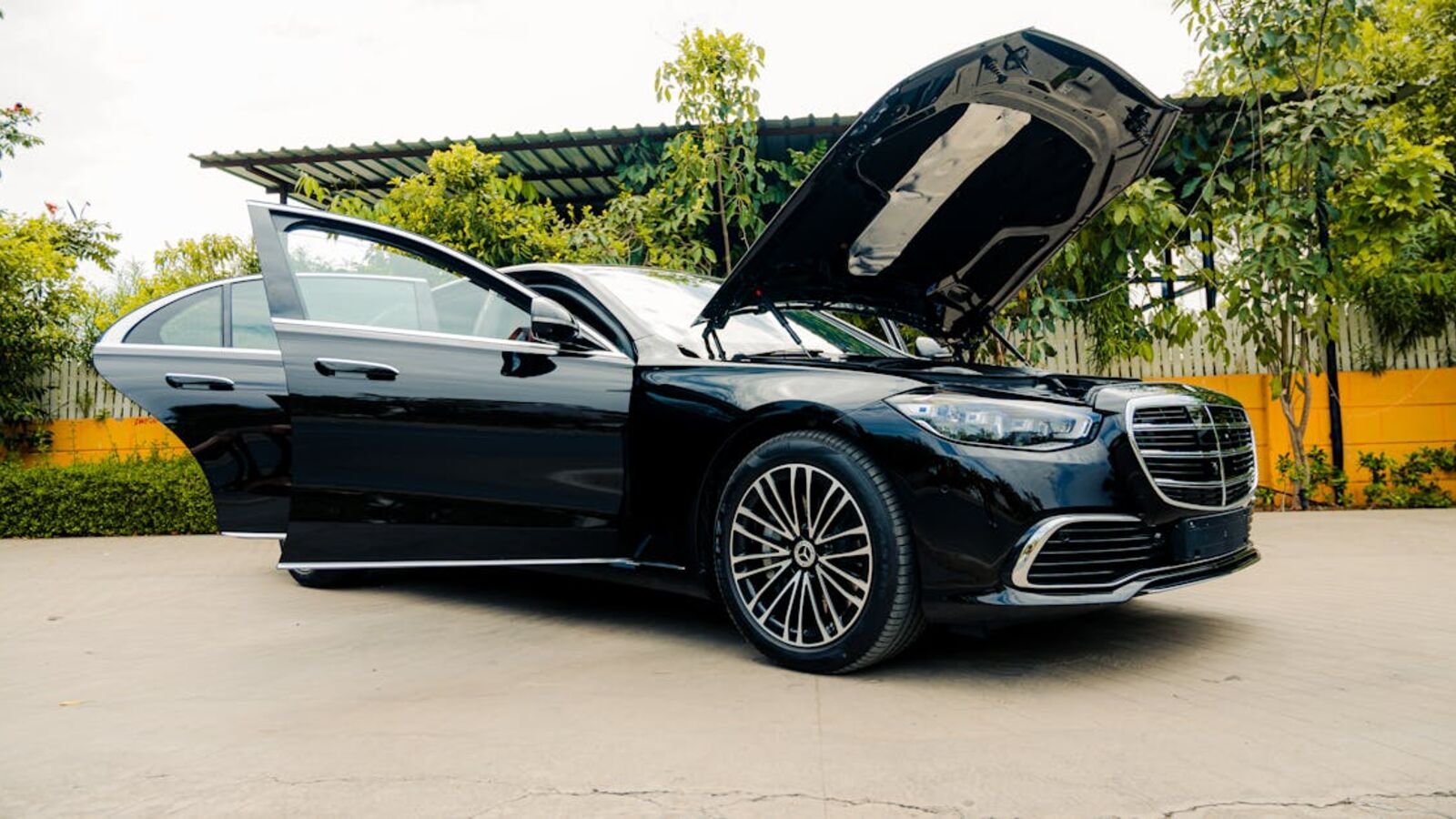 Black luxury sedan with open hood parked outdoors, showcasing elegance.