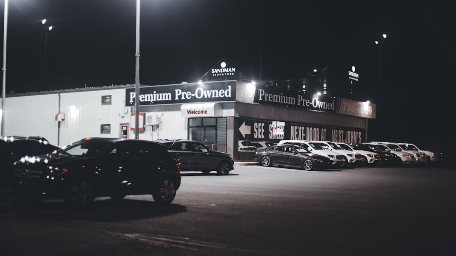 Illuminated car dealership lot showcasing premium pre-owned vehicles at night.