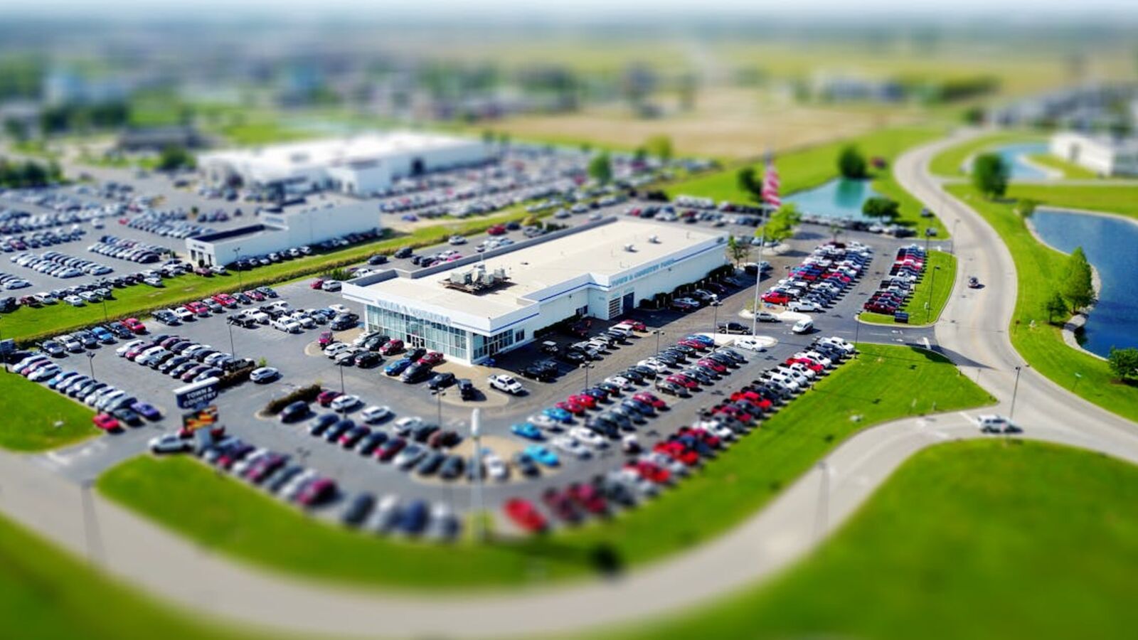 Выкуп авто в залоге в Санкт-Петербурге — Aerial high-angle view of a bustling car dealership surrounded by parked cars in a green landscape.