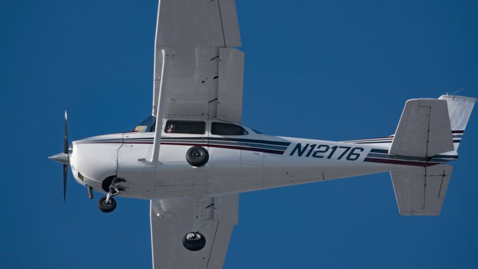 High-angle view of a private airplane soaring in a clear blue sky, showcasing aviation and freedom.