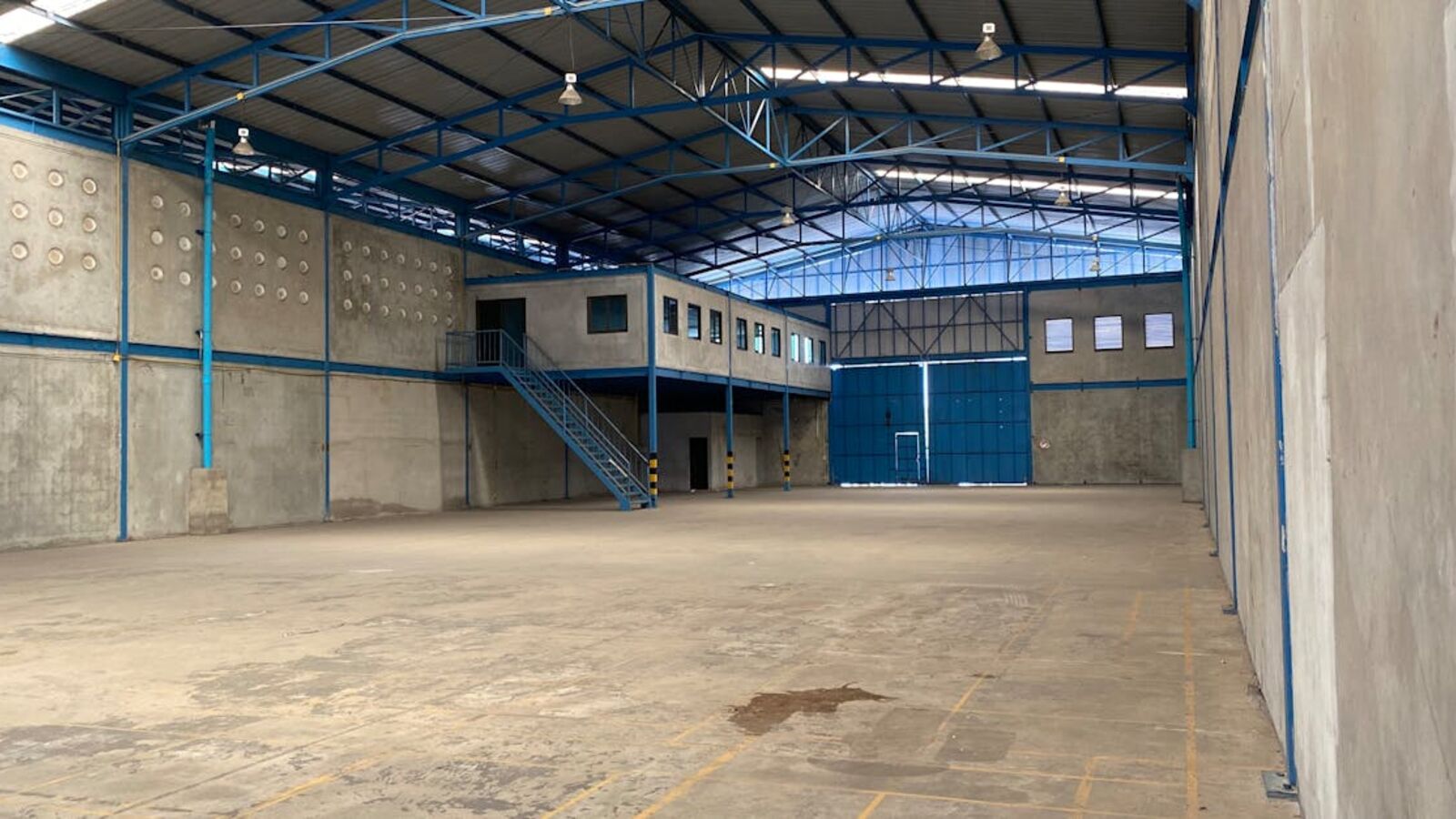 Empty warehouse with blue steel frame and concrete walls in Bangkok.
