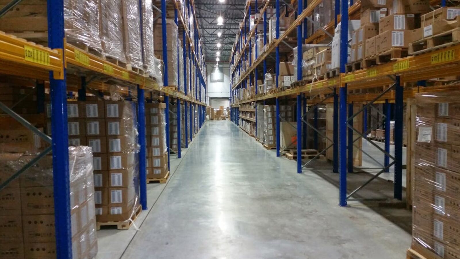 Interior view of a large warehouse aisle lined with stacks of organized cardboard boxes.