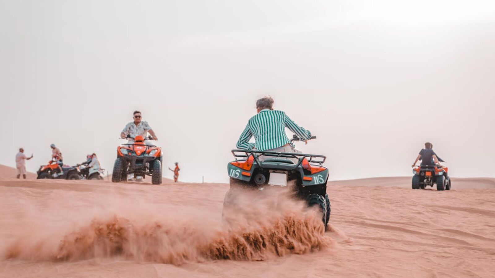 Capture the thrill of an ATV ride through scenic desert dunes under bright sunlight.