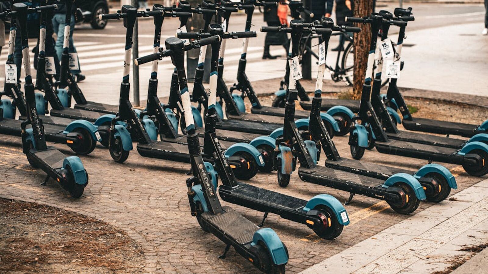Выкуп скутеров в Санкт-Петербурге — Multiple electric scooters parked on a cobblestone street in Florence, Italy, ready for use.
