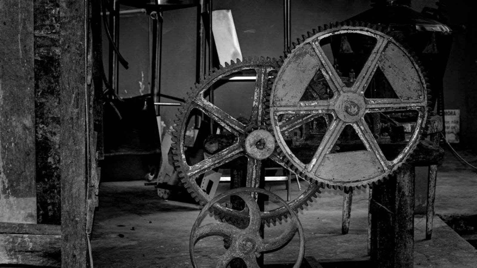 Black and white photo capturing rustic gears in an industrial setting.