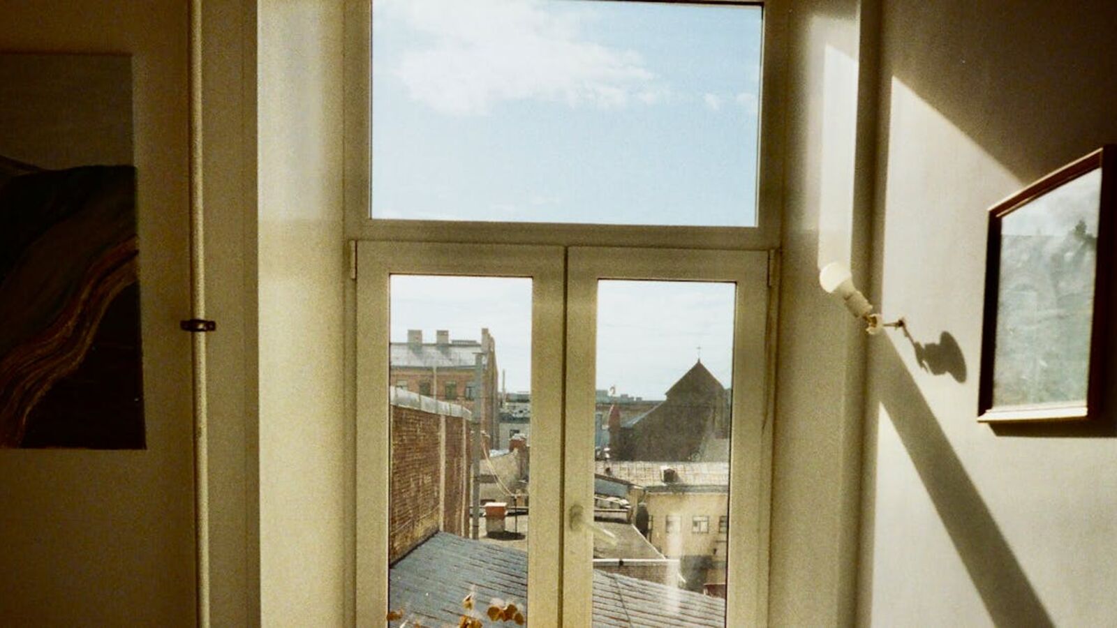 Warm indoor scene capturing a window view of Saint Petersburg's architecture and rooftops under a blue sky.
