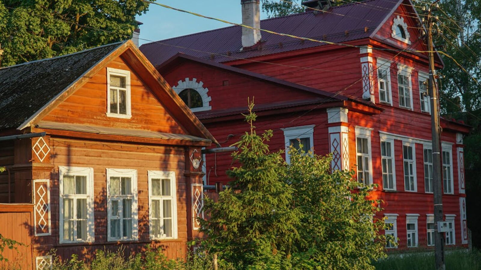 Выкуп дач в Санкт-Петербурге и Ленинградской области — Beautiful wooden houses in rural Novgorod, Russia, showcasing traditional architecture amidst lush greenery.