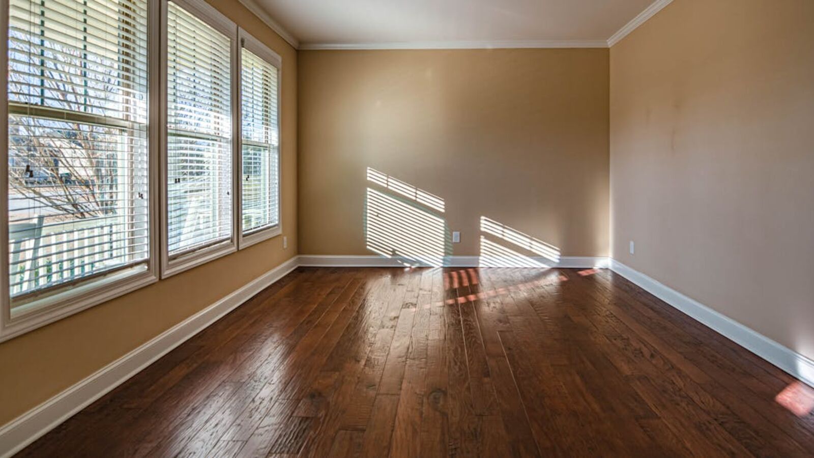 Выкуп комнат в Санкт-Петербурге — Sunlit empty room with hardwood floors and large windows, ideal for home staging.
