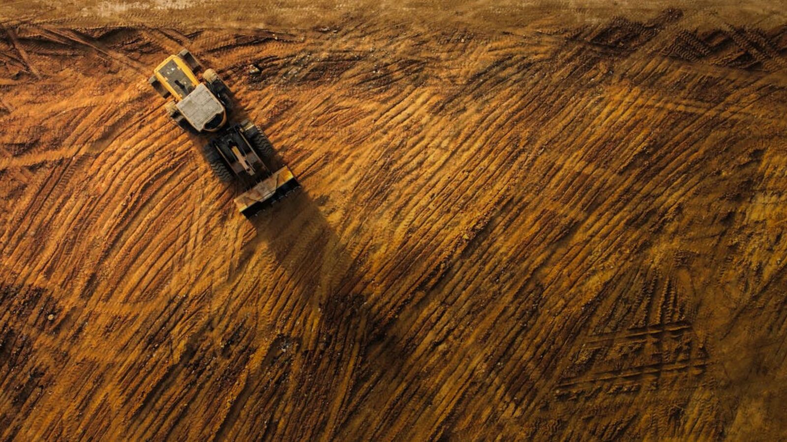 Top-down view of a bulldozer moving earth on a large construction site.