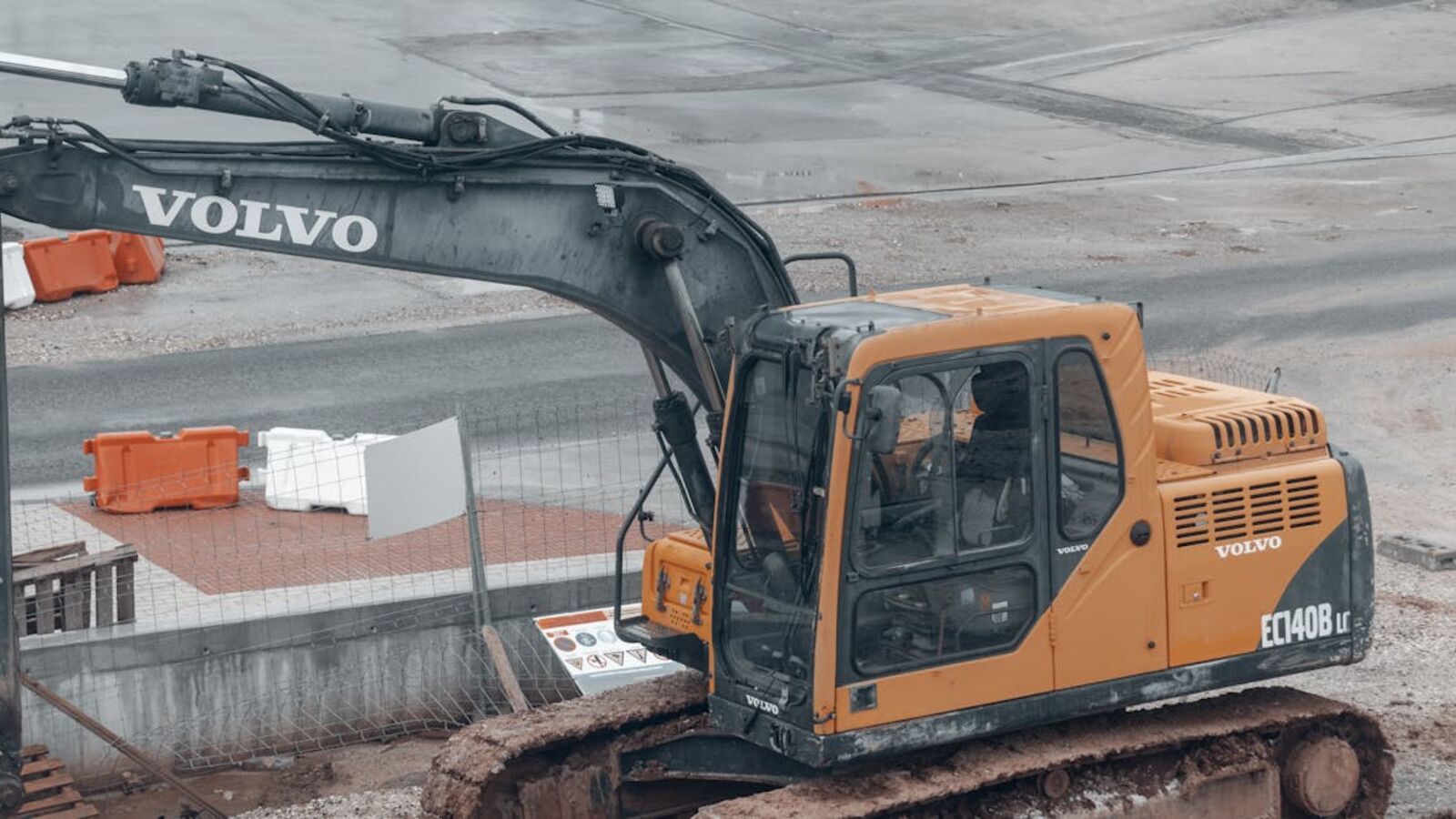 A yellow Volvo excavator at a construction site with muddy tracks.