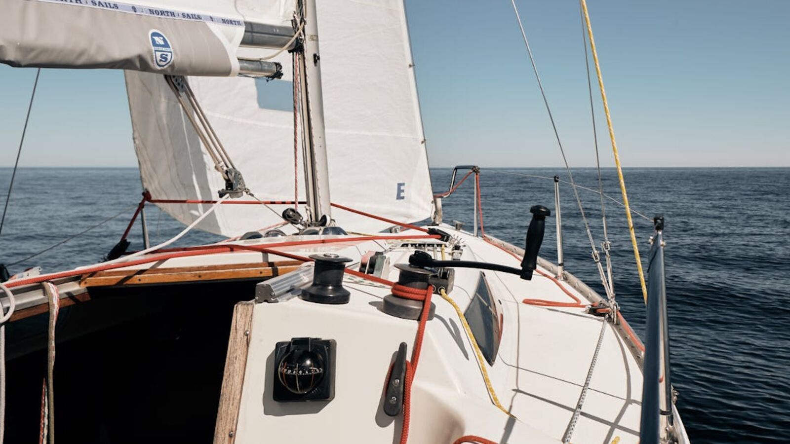 A sailboat navigating through the open sea under clear skies.
