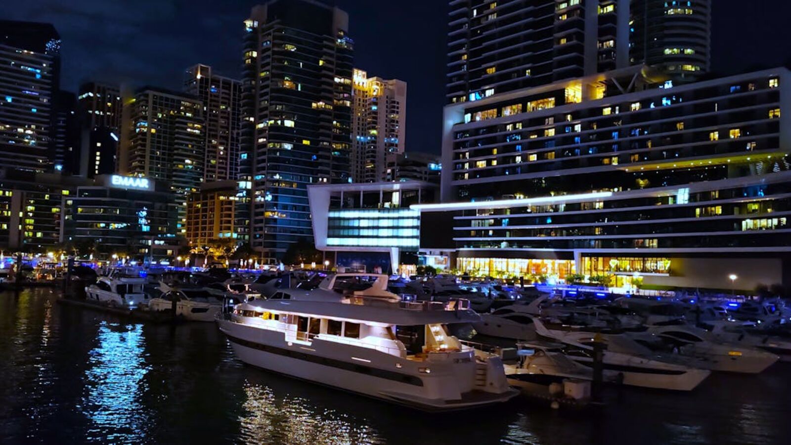 Stunning night view of Dubai Marina with yachts docked and illuminated skyscrapers.